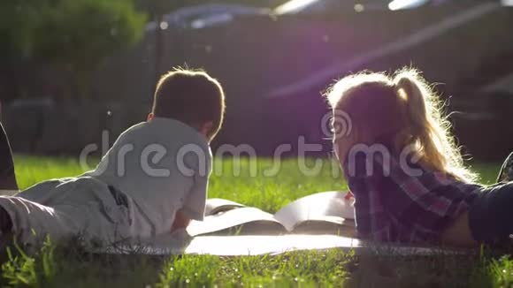 友谊小男孩和小女孩躺在草地上在户外阳光下休息时看书中的图片视频的预览图
