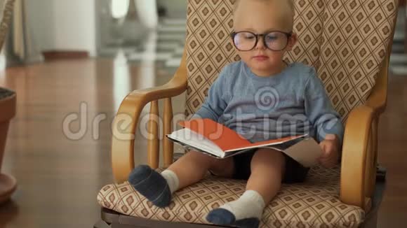 小男孩坐在椅子上拿着一本书视频的预览图