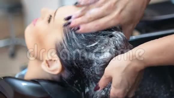 用专业洗发水为深色头发的女士洗头视频的预览图