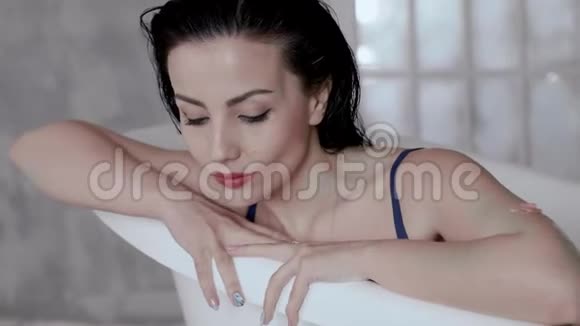 一位年轻女士在装满牛奶的浴缸里的肖像女脸的特写视频的预览图