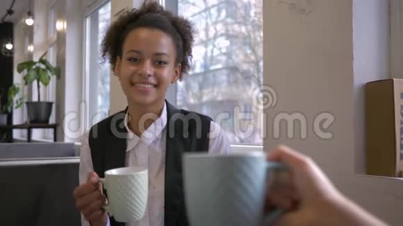 微笑的黑女孩在咖啡馆和朋友喝杯茶让叮当作响视频的预览图
