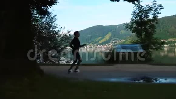 跟踪镜头年轻女子在湖边和山上奔跑清晨在公园里训练女孩慢跑高山泽尔姆看到奥斯特视频的预览图