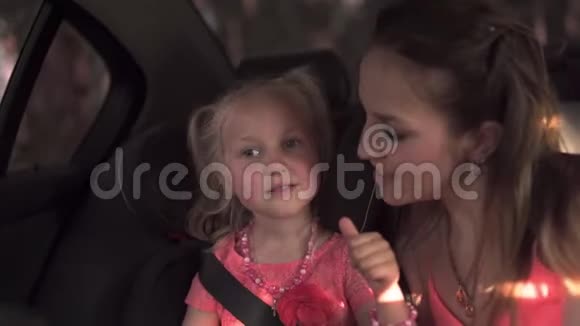 安全带系上儿童车座母亲和女儿年轻的白种人妈妈穿着夏装鲜艳生动视频的预览图