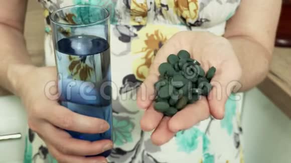 有螺旋藻药丸和一杯水的女人健康生活方式概念视频的预览图