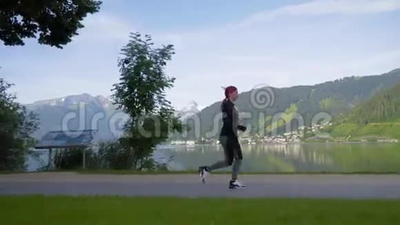 跟踪镜头年轻女子在湖边和山上奔跑清晨在公园里训练女孩慢跑高山泽尔姆看到奥斯特视频的预览图