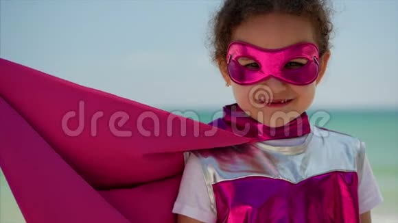 肖像可爱的小女孩在超级英雄服装穿着粉红色斗篷和面具的英雄坐在飞机上视频的预览图