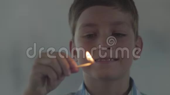 小男孩在黑暗的烟雾弥漫的房间里玩火柴的特写孩子笑着点燃火柴孩子视频的预览图