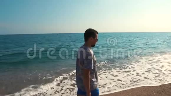 戴着深色太阳镜的成年长胡子男子在热带海岸散步视频的预览图