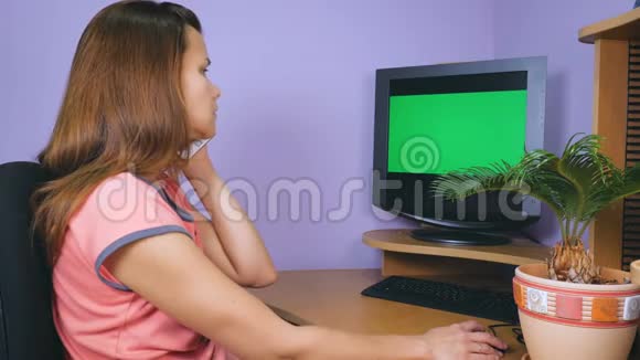 一个年轻的女人坐在家里的办公室里用手机说话视频的预览图