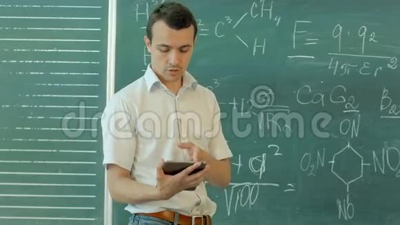 微笑男老师拿着数字平板电脑对着教室的黑板视频的预览图