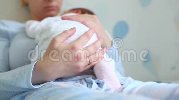 年轻美丽的母亲抱着她可爱的孩子她睡在妈妈胸前在家里视频的预览图