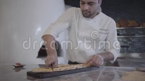 在现代餐厅的厨房里厨师穿着白色制服把刚烤好的胖子切成块躺在木板上视频的预览图