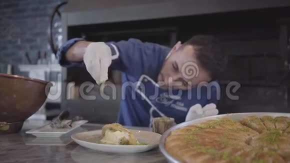 厨师穿着蓝色制服和白色乳胶手套准备为东方甜库纳法提供奶酪并撒上奶酪视频的预览图