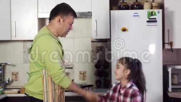 爸爸和快乐的小女孩黑发在厨房玩耍视频的预览图