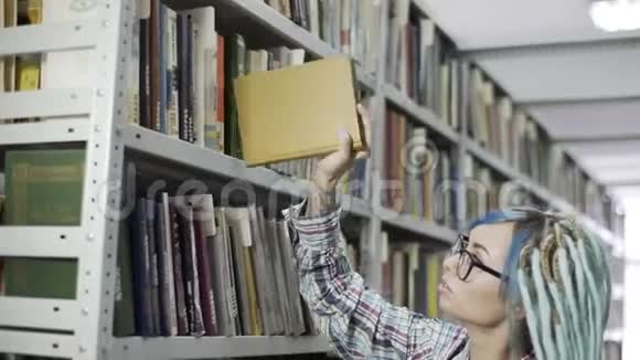 女时髦的大学生在书架上找书视频的预览图
