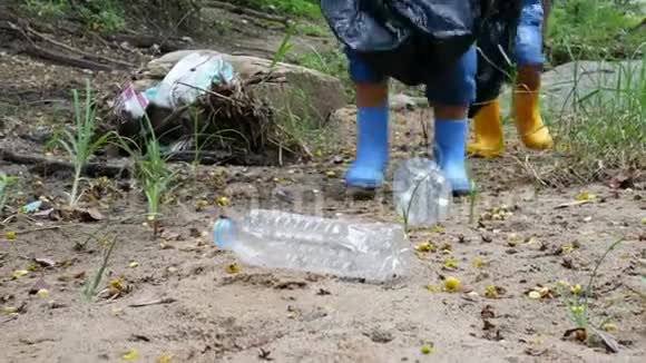 亚洲的小孩子正在公共河边捡垃圾和塑料瓶装在黑色的袋子里视频的预览图