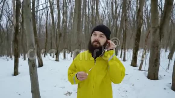 长胡子的运动员戴上耳机在白雪皑皑的冬林中奔跑视频的预览图