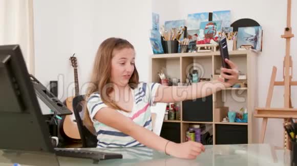十几岁的女孩在她的智能手机上做愚蠢和有趣的自我视频的预览图