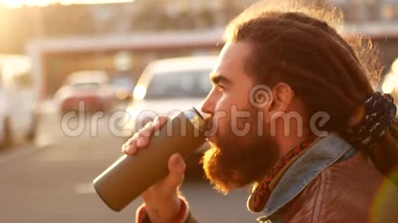 一个男人正在街上喝热水瓶里的茶秋环境消费的概念家庭咖啡视频的预览图