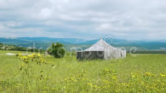 一个大的帆布帐篷矗立在山里的一片田野中间视频的预览图