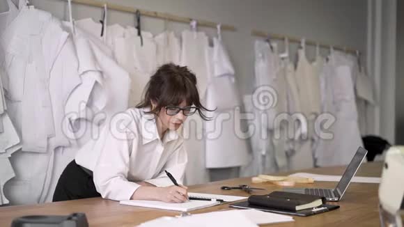 女时装设计师靠在桌子上做笔记视频的预览图