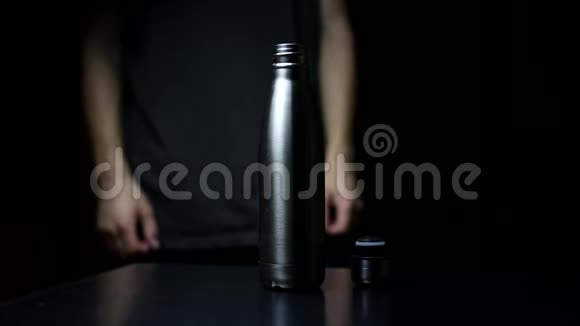 工作室形象特写男手放在盖子上可重复使用钢热水瓶在黑色背景上视频的预览图
