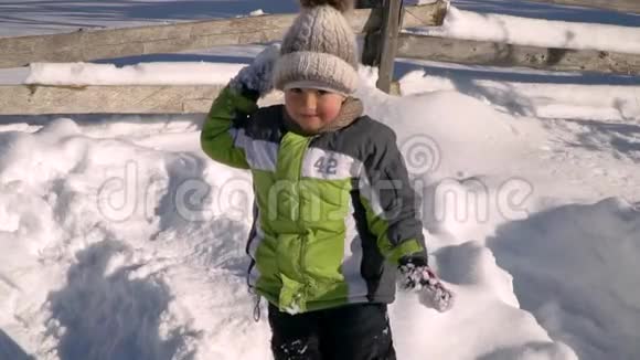 冬天小可爱的男孩在外面的雪地里玩耍背景是一片雪林那个男孩朝雪扔视频的预览图