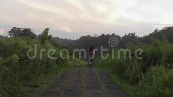 穿着紧身衣的女孩沿着丛林中的小路奔跑视频的预览图