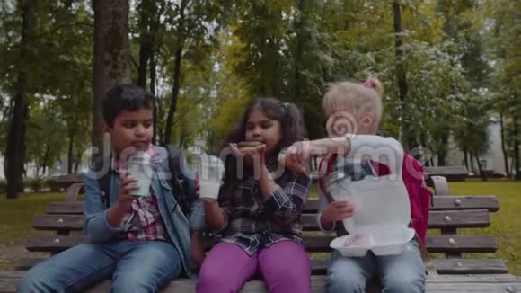 混合种族群体的学校孩子一起吃午餐在学校附近的户外休息回到学校的概念慢慢视频的预览图