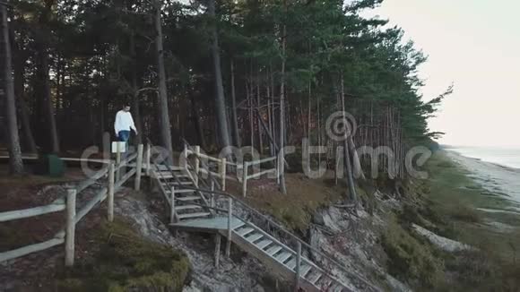 夏天一个男人从森林海岸的海滩上走下楼梯蟠开视频的预览图