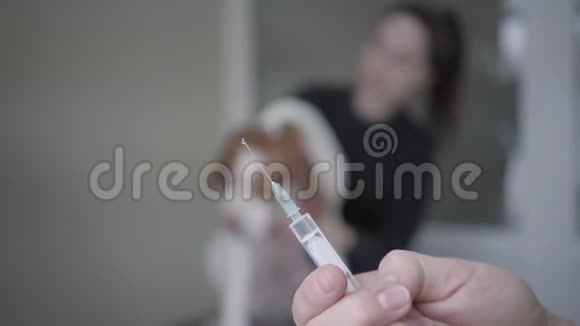 兽医在前台的注射器里拿起药女人抚摸她的大狗的模糊身影视频的预览图