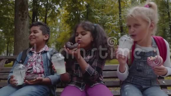 混合种族群体的学校孩子一起吃午餐在学校附近的户外休息回到学校的概念慢慢视频的预览图