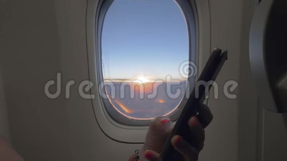 在飞机上用手机背景为日出的飞机窗口视频的预览图