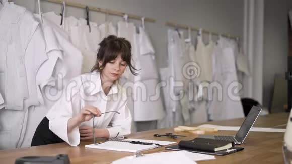 女时装设计师在带笔记本电脑的缝纫工作室工作视频的预览图