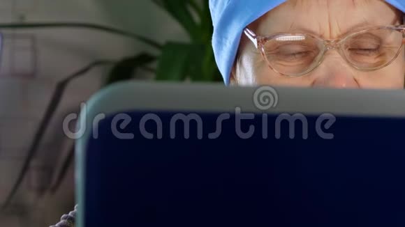 戴眼镜的老年妇女使用笔记本电脑视频的预览图