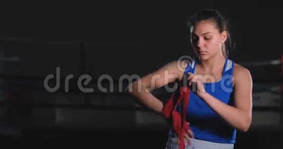一位美丽的女战士正在准备慢动作的战斗手上的拳击绷带视频的预览图