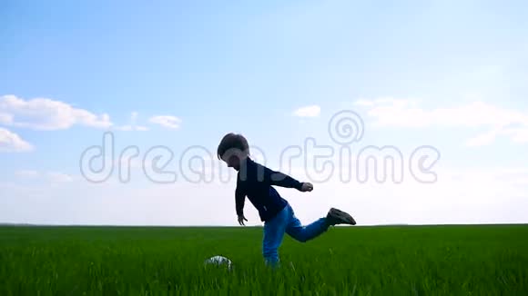 一个孩子高兴地踢足球慢悠悠地跑过草地视频的预览图
