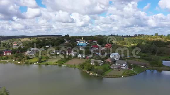 在湖边的一座小山上鸟瞰美丽的村庄景观摄像机从右到左跟踪视频的预览图