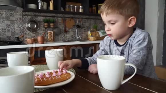 一个忧郁的小男孩坐在一张桌子旁桌上放着一杯圆茶和蛋糕舔他的手指肖像视频的预览图