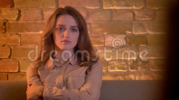 悲伤的年轻少女在客厅里看电视悲伤地拥抱自己的肖像视频的预览图