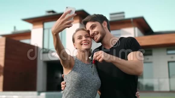幸福夫妇在住宅外用房子钥匙拍自拍照片视频的预览图