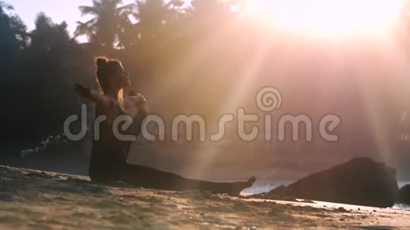 穿着黑色运动服的年轻女子坐在沙滩上视频的预览图