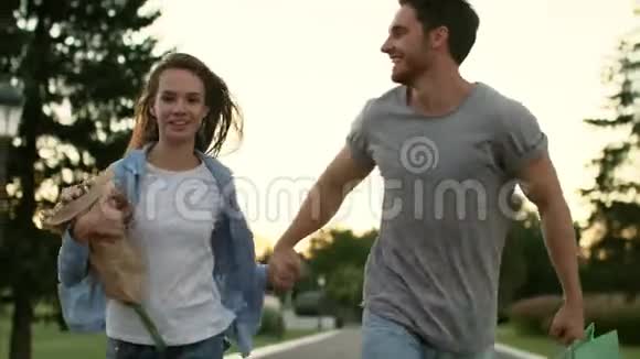 快乐的一对花在夏天的公园里奔跑恋爱中的情侣视频的预览图