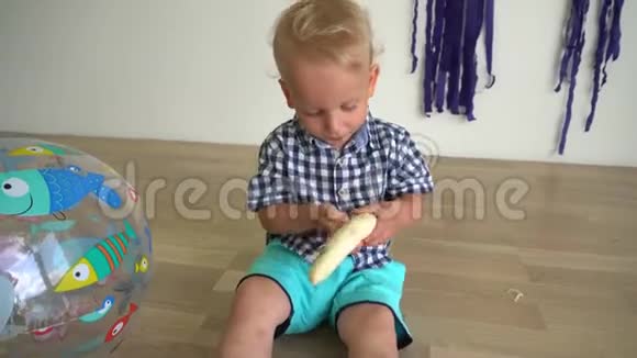 两岁的小男孩坐在地板上吃香蕉万向节运动视频的预览图