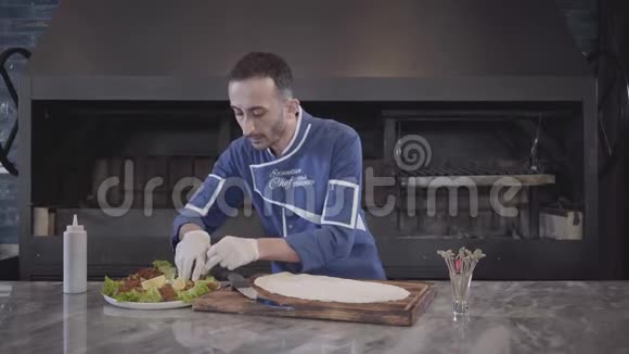 一个穿着厨师制服的人准备用拉瓦什包裹的盘子厨师手小心地把肉馅撒在皮塔上土耳其菜视频的预览图