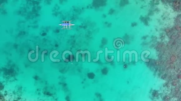 一艘孤独的小船在绿松石透明的海洋中的空中俯视里面有珊瑚礁和深蓝色的中空视频的预览图