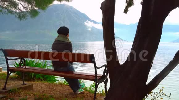 黑山悬崖上坐在海边的女人的后景视频的预览图