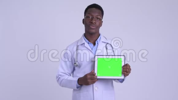 年轻快乐的非洲男医生一边讲一边显示数字平板电脑视频的预览图