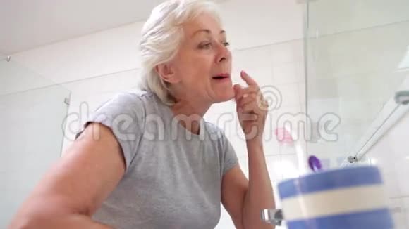 高级妇女在浴室镜子里检查皮肤视频的预览图
