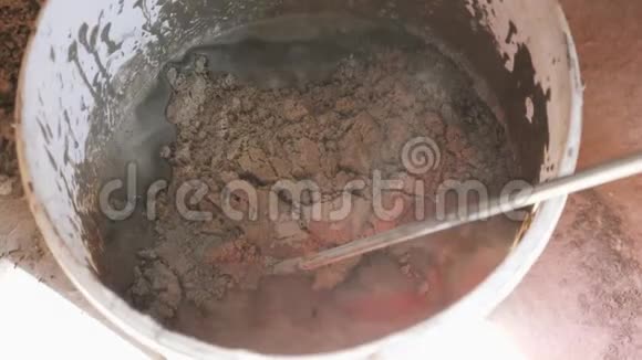 用长钻拌水泥胶或砂浆工人用长钻把水泥胶拌在水桶里砂水水泥混合搅拌视频的预览图